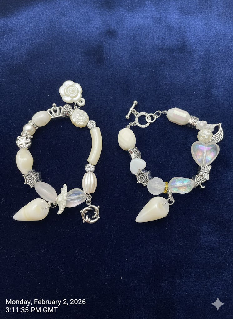 Handcrafted Oceanic Archive jewellery set by Iris By Hazel featuring resin beads, vintage alloy dolphin and feather charms, and sparkling rhinestones on a white dark blue.